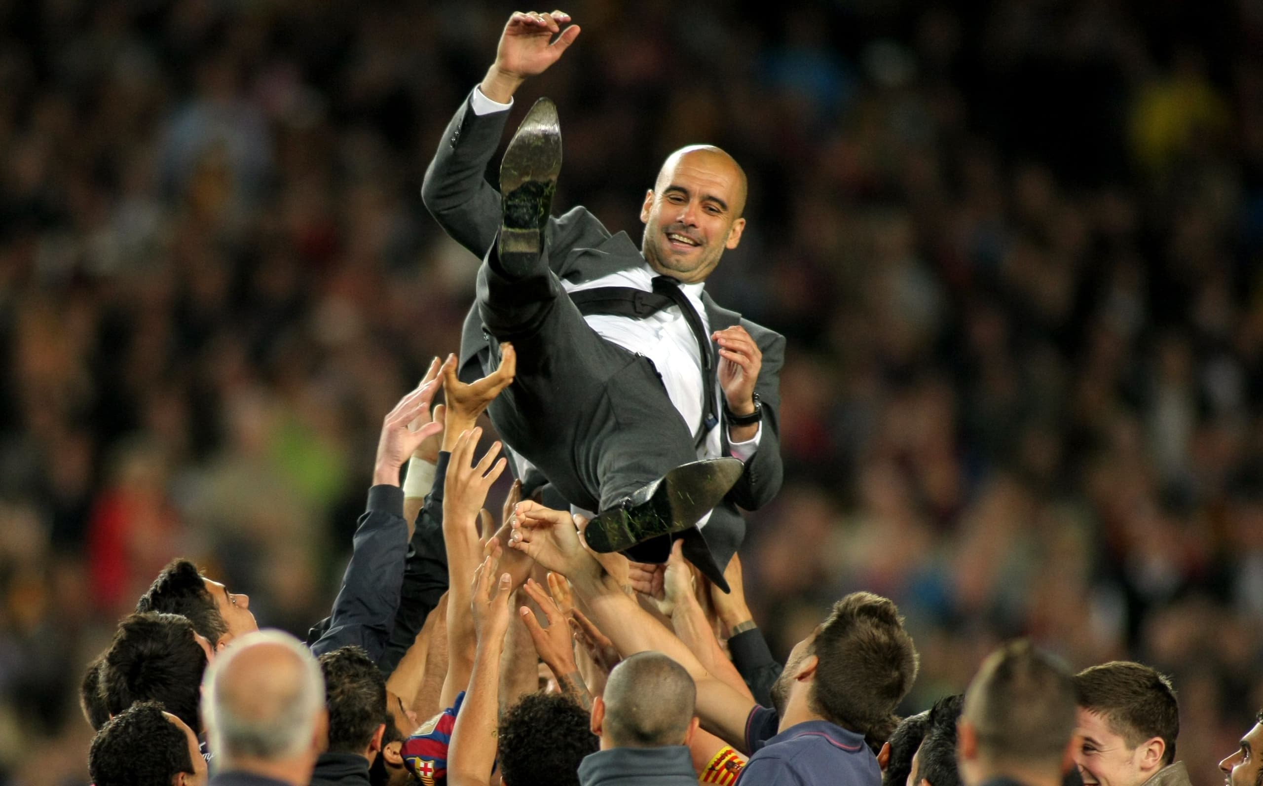 Football manager being carried in the air by his team