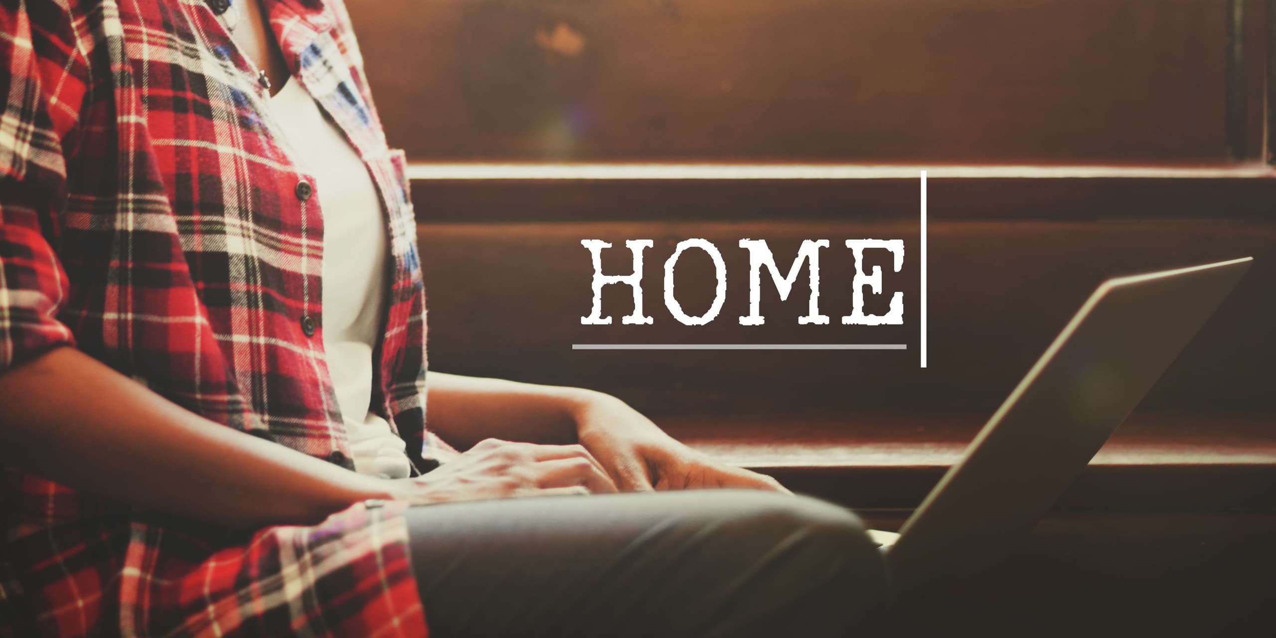 Person wearing an unbuttoned checked shirt searching on laptop