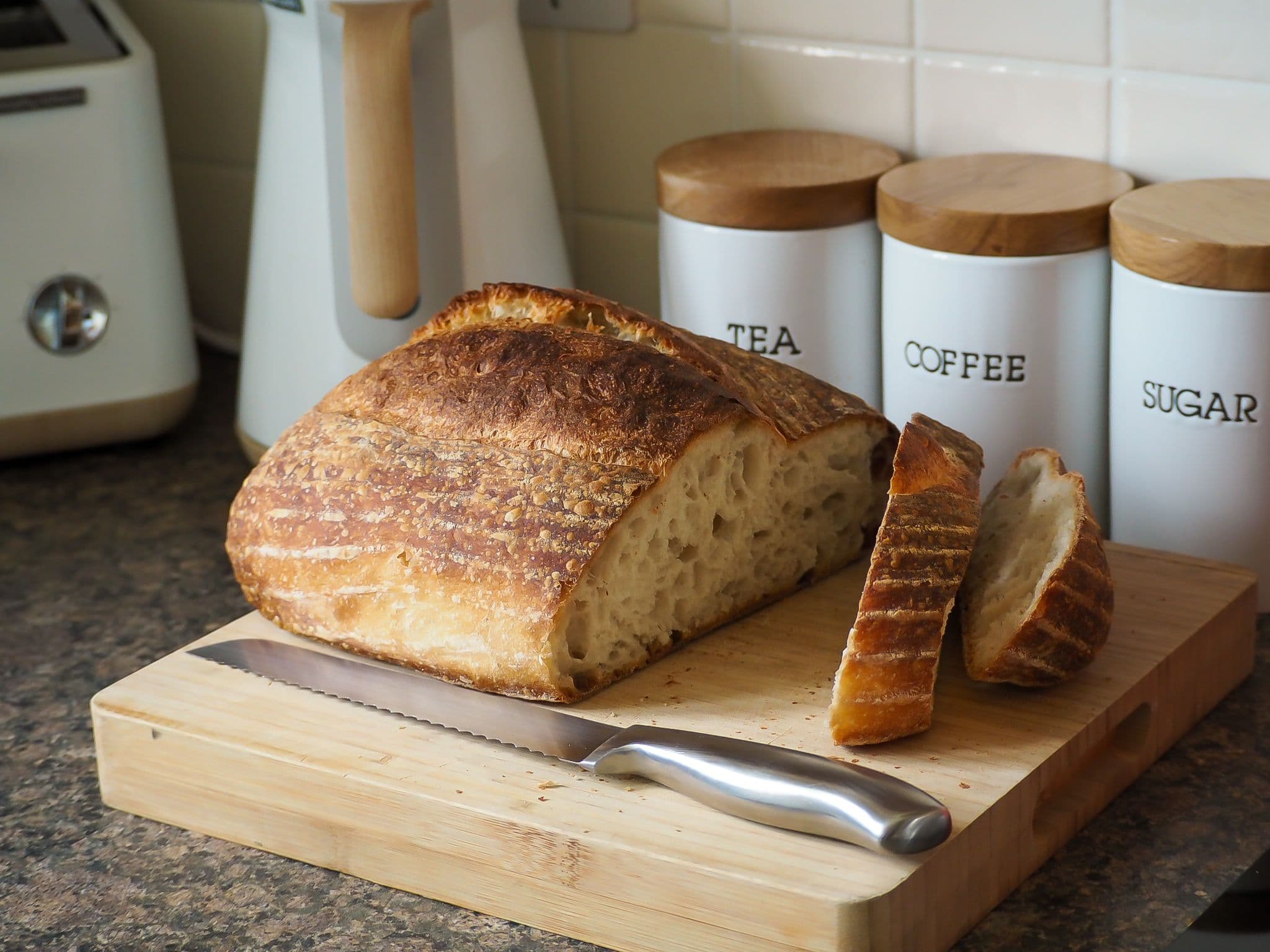 Sliced bread on a chopping board with bread knife