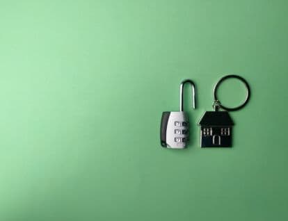 Open lock next to a metal house on a keyring