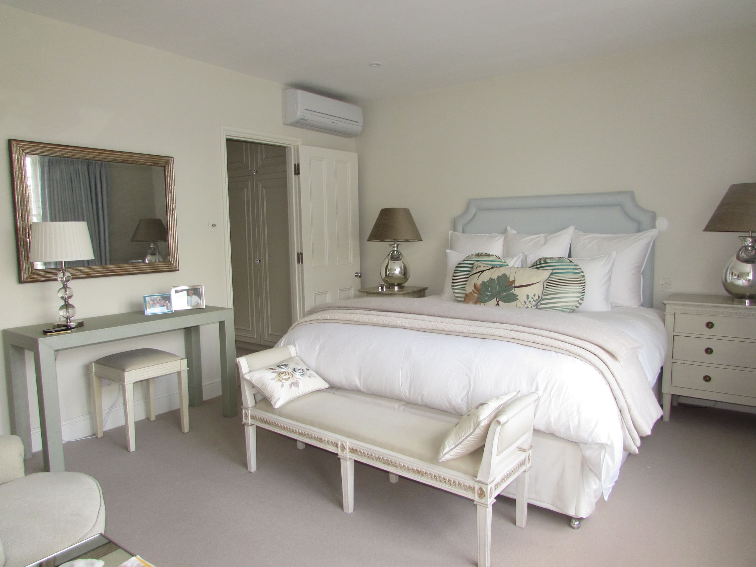 Bedroom with double bed ottoman bedside tables mirror and dressing table