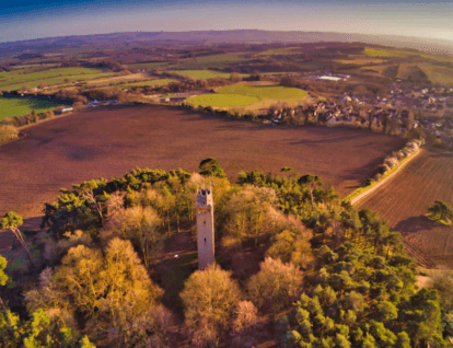 Aerial shot of country side – showing fields and small village in the distance